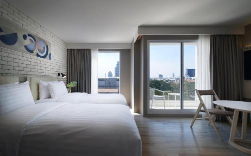 a hotel room with two beds and a large window at Shama Yen-Akat Bangkok in Bangkok
