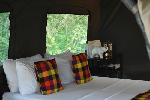 a bedroom with a bed with plaid pillows and a window at Big Game - Wilpattu by Eco Team in Wilpattu