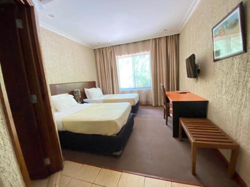 a hotel room with two beds and a desk at Sangana Lodge in Moshi