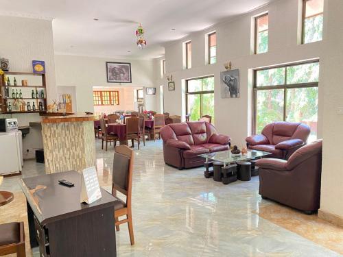 a living room with leather chairs and tables and a bar at Sangana Lodge in Moshi
