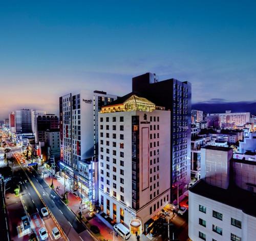 a tall white building in a city at night at Hotel Leo in Jeju