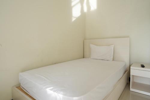 a small bedroom with a white bed and a nightstand at Urbanview Hotel Syariah Casa Azmya Yogyakarta by RedDoorz in Kejayan