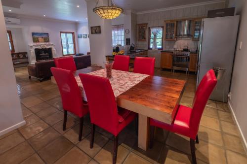 a kitchen and dining room with a wooden table and red chairs at Eden Studios in Riebeek-Kasteel