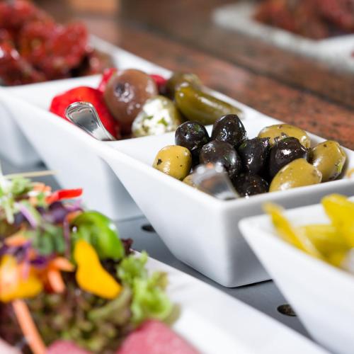 a row of white bowls filled with olives and vegetables at Spundloch- das Hotel & Weinrestaurant in Veitshöchheim