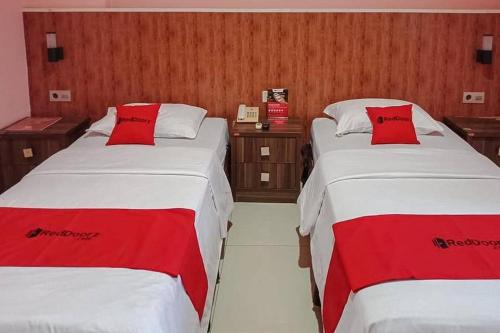 2 camas en una habitación de hotel con almohadas rojas en RedDoorz @ Sorong City Center en Sorong