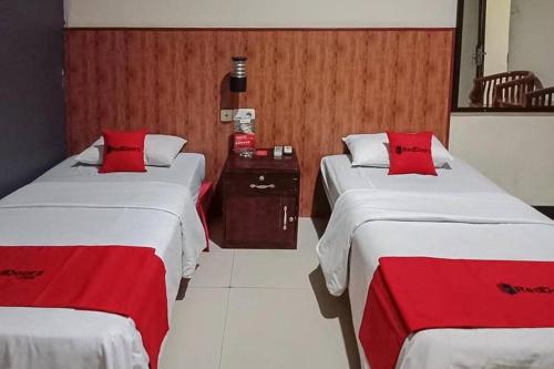 two beds in a hotel room with red pillows at RedDoorz @ Sorong City Center in Sorong