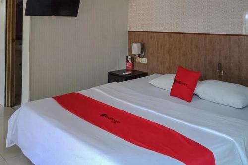 Una gran cama blanca con una manta roja. en RedDoorz @ Sorong City Center, en Sorong