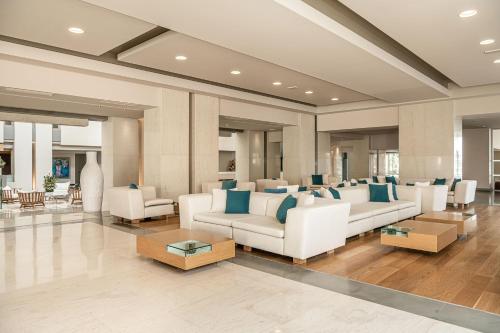 a living room with white couches and blue pillows at Avra Imperial Hotel in Kolymvari