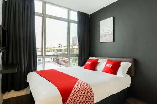 a bedroom with a large bed with red pillows and a window at OYO 90460 Hotel Kl2f Rest & Go in Shah Alam