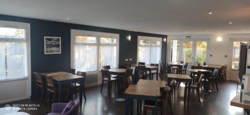 a restaurant with wooden tables and chairs and windows at Kyriad Mulhouse Est - Lutterbach in Lutterbach