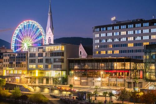 a large building with a ferris wheel in the background at voco® Villach, an IHG Hotel in Villach