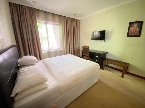 a hotel room with a bed and a television at Sangana Lodge in Moshi