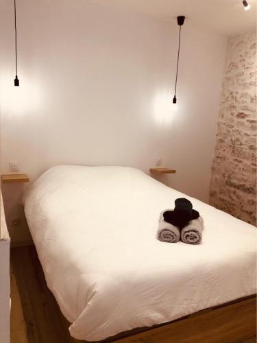 - un lit blanc avec un chapeau et des serviettes dans l'établissement Le jungle charmant appartement avec extérieur, à Nîmes