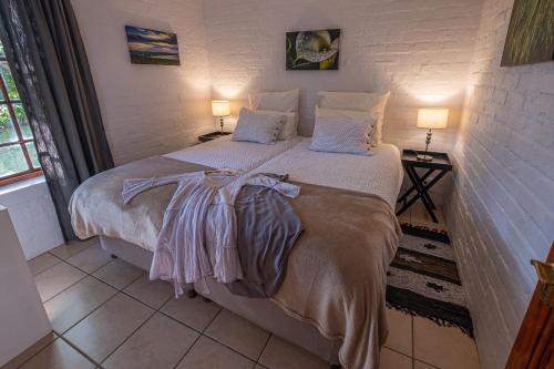 a bedroom with a large bed with two lamps at Eden Studios in Riebeek-Kasteel