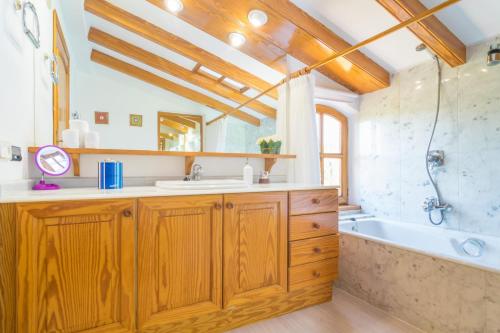 W łazience znajdują się drewniane szafki, wanna i umywalka. w obiekcie Villa Marjals 16 w mieście Muro