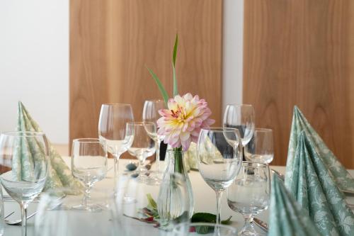 a table with wine glasses and a flower in a vase at Cusanus Akademie - Accademia Cusanus in Bressanone