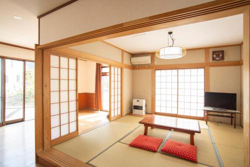 a living room with a table and some windows at Kusatsu Onsen Eidaya in Kusatsu