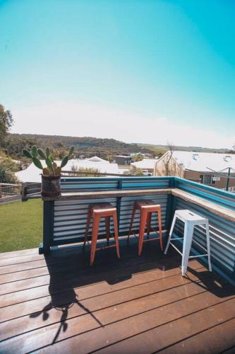 two chairs and two stools sitting on a deck at Coastaways in Port Campbell