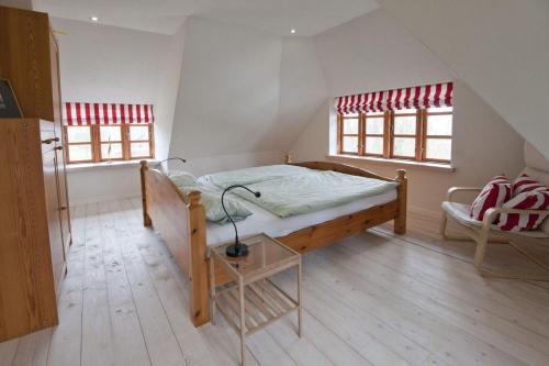 a bedroom with a bed and a chair and two windows at Kapitänshaus in Brodersby