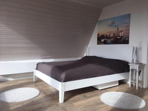 ein Schlafzimmer mit einem weißen Bett und einem Gemälde an der Wand in der Unterkunft Weitblick in Brodersby