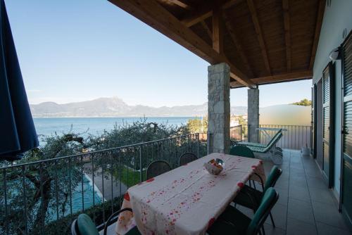 a table on a balcony with a view of the water at ApartmentsGarda - Canevini Residence in Torri del Benaco