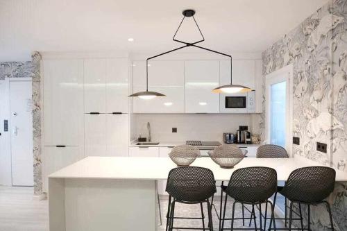 a kitchen with a white counter and some chairs at Apartamento alameda in Pontevedra