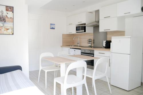 - une cuisine blanche avec une table en bois et des chaises blanches dans l'établissement Sunny apartment in heart of Nice Old Town, à Nice