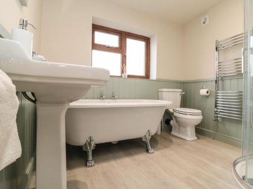 uma casa de banho com uma banheira, um lavatório e um WC. em Eskside Cottage em Whitby