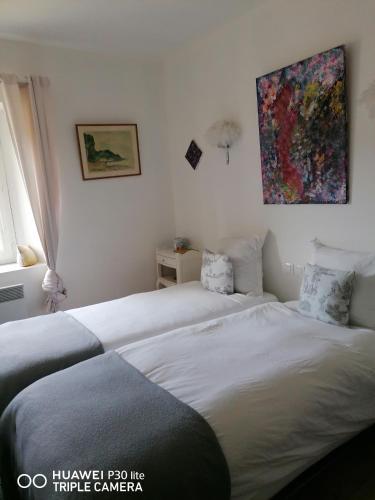 une chambre avec deux lits et un tableau au mur dans l'établissement GÎTE AU TILLEUL pour 8 personnes, à Mariac