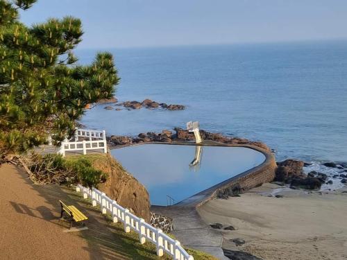 a swimming pool on the beach next to the ocean at Maison de pêcheurs in Saint-Quay-Portrieux