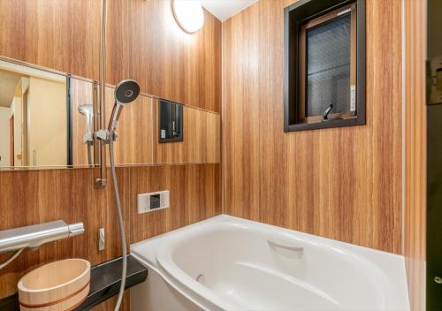 a bathroom with a tub and a window and a mirror at YADOYA Yanagitori East in Tokyo