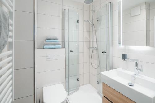 baño blanco con ducha y lavamanos en Urlaubs-Residenz Norderney, en Norderney