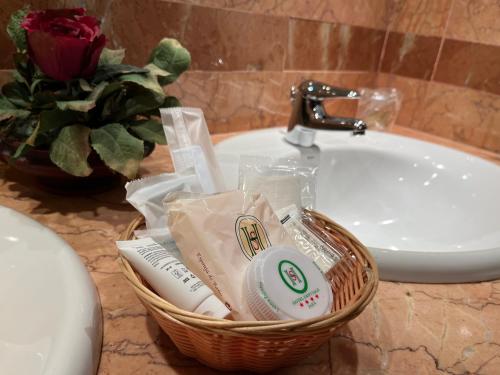 uma cesta de produtos de higiene pessoal num balcão de casa de banho ao lado de um lavatório em Santiago em Linares
