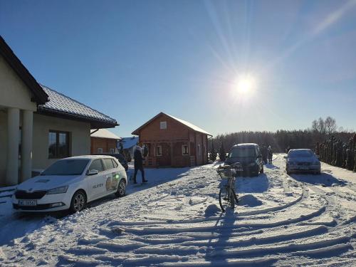 a bike parked on a snow covered street with cars at Noclegi "LAS WYPAS" Trzcianka in Trzcianka