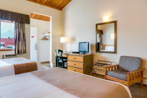 a hotel room with two beds and a desk and a mirror at Rocky Mountain Ski Lodge in Canmore