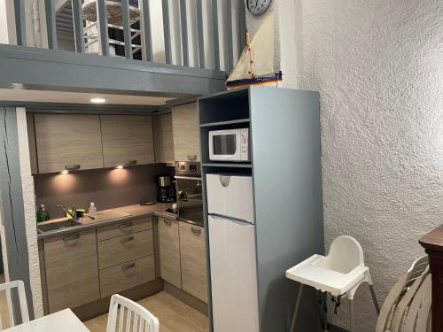 une petite cuisine avec un réfrigérateur et un micro-ondes dans l'établissement Collioure, bel appartement de 40m2 avec balcon et parking, à Collioure