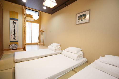Dos camas en una habitación con dos ventanas. en 谷町君 星屋 離宮ノ宿 二条城, en Kioto