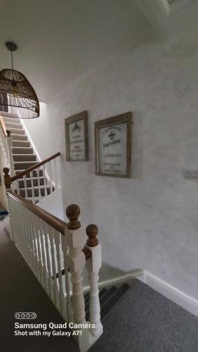 a white staircase with two pictures on the wall at Homestay in Poole