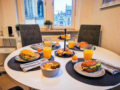een tafel met borden eten en sinaasappelsap bij Zwickau Innenstadt Deluxe Apartment in Zwickau