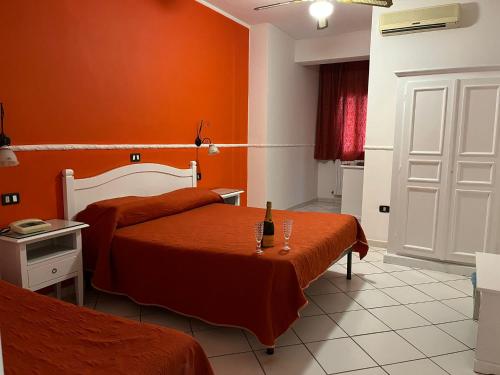 una camera d'albergo con due letti e pareti arancioni di Hotel Caribe a Casalnuovo di Napoli