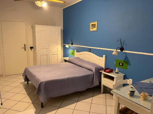a bedroom with a bed and a blue wall at Hotel Caribe in Casalnuovo di Napoli