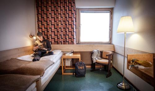 a woman sitting on a bed in a room at Köja Fjällhotell in Edsåsdalen