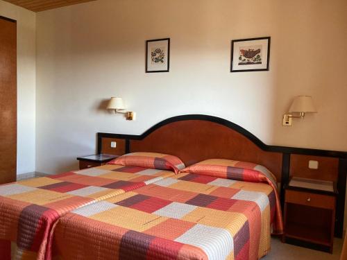 a hotel room with a bed and two lamps on the wall at Mas Espuella in Argelaguer
