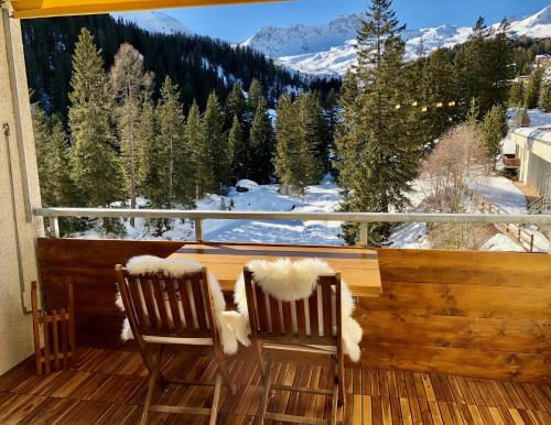 two chairs on a balcony with a view of a snowy mountain at Calarosa Boutique Apartment Arosa in Arosa