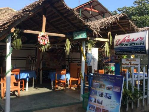 a restaurant with tables and chairs and a roof at Viraj's Garden in Tangalle