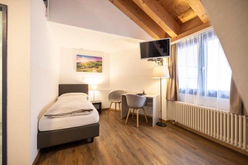 a bedroom with a bed and a desk in a room at Hotel Restaurant Alte Brauerei in Celerina