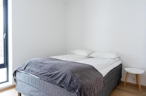 a white bedroom with a bed with a table at King's Park in Tromsø