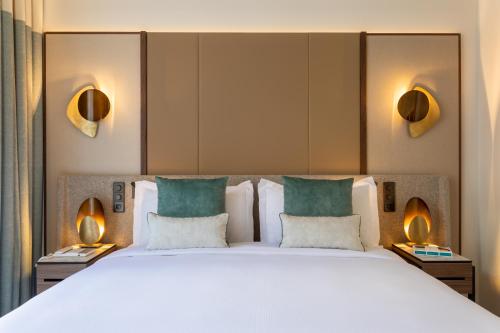 a large bed in a hotel room with two lamps at InterContinental Paris Champs Elysées Etoile, an IHG Hotel in Paris