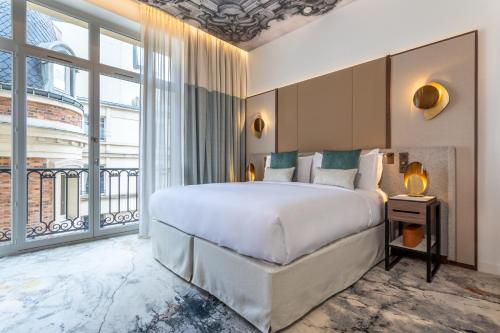 a bedroom with a large bed and a large window at InterContinental Paris Champs Elysées Etoile, an IHG Hotel in Paris