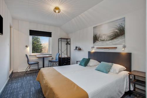 Cette chambre comprend un grand lit et une table. dans l'établissement Hotel de Logerij Renesse, à Renesse